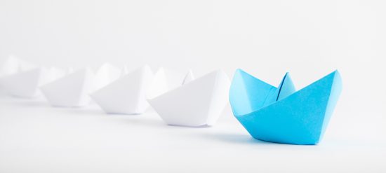 Leadership concepts with blue paper ship leading among white